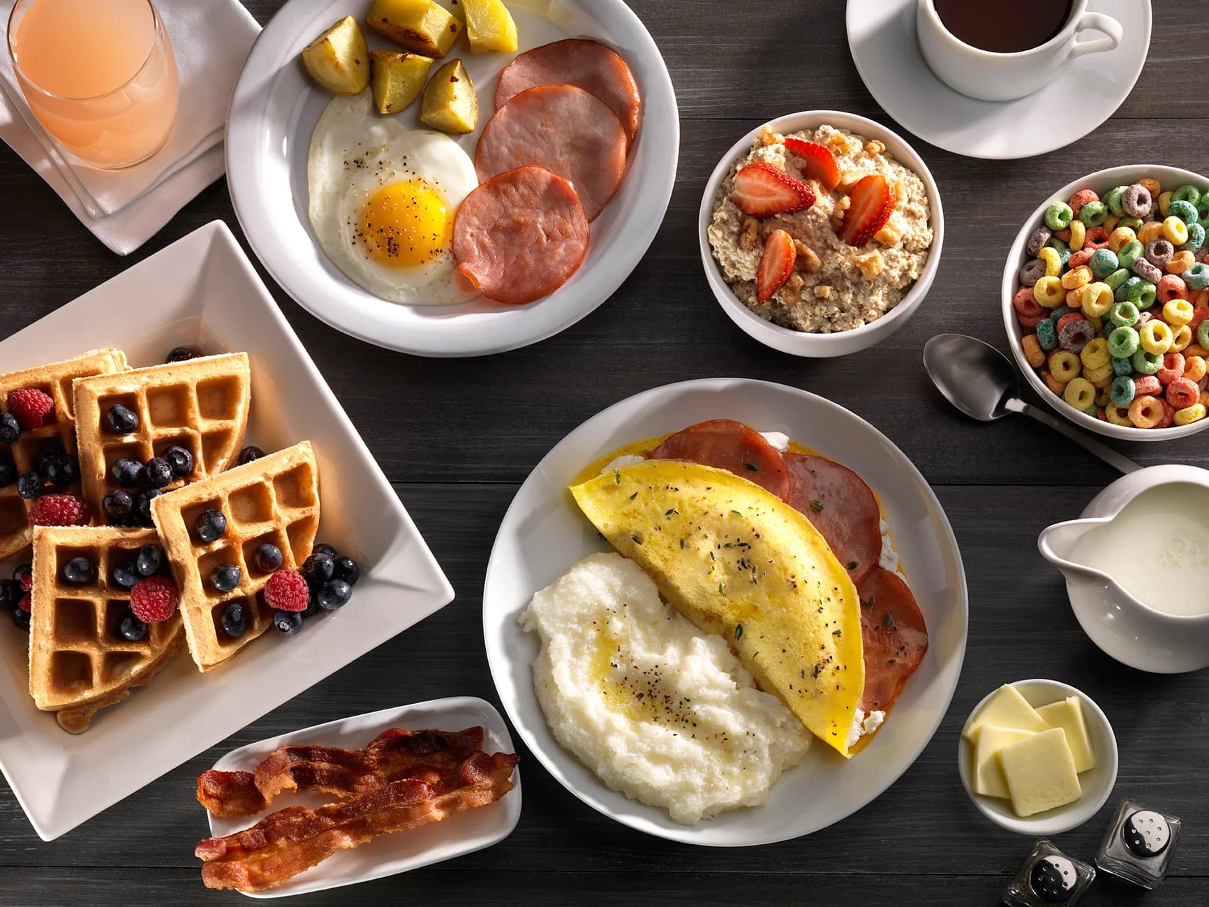 An Embassy Suites breakfast spread with waffles, eggs, an omelet, fruit, cereal and coffee