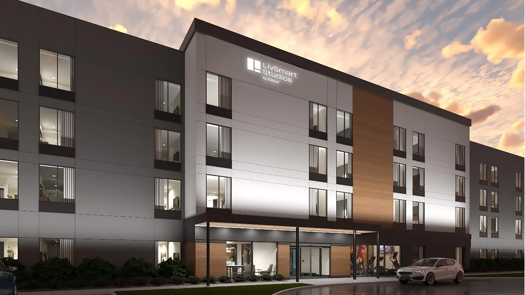 Rendering of a four-story LivSmart Studios by Hilton hotel at dusk