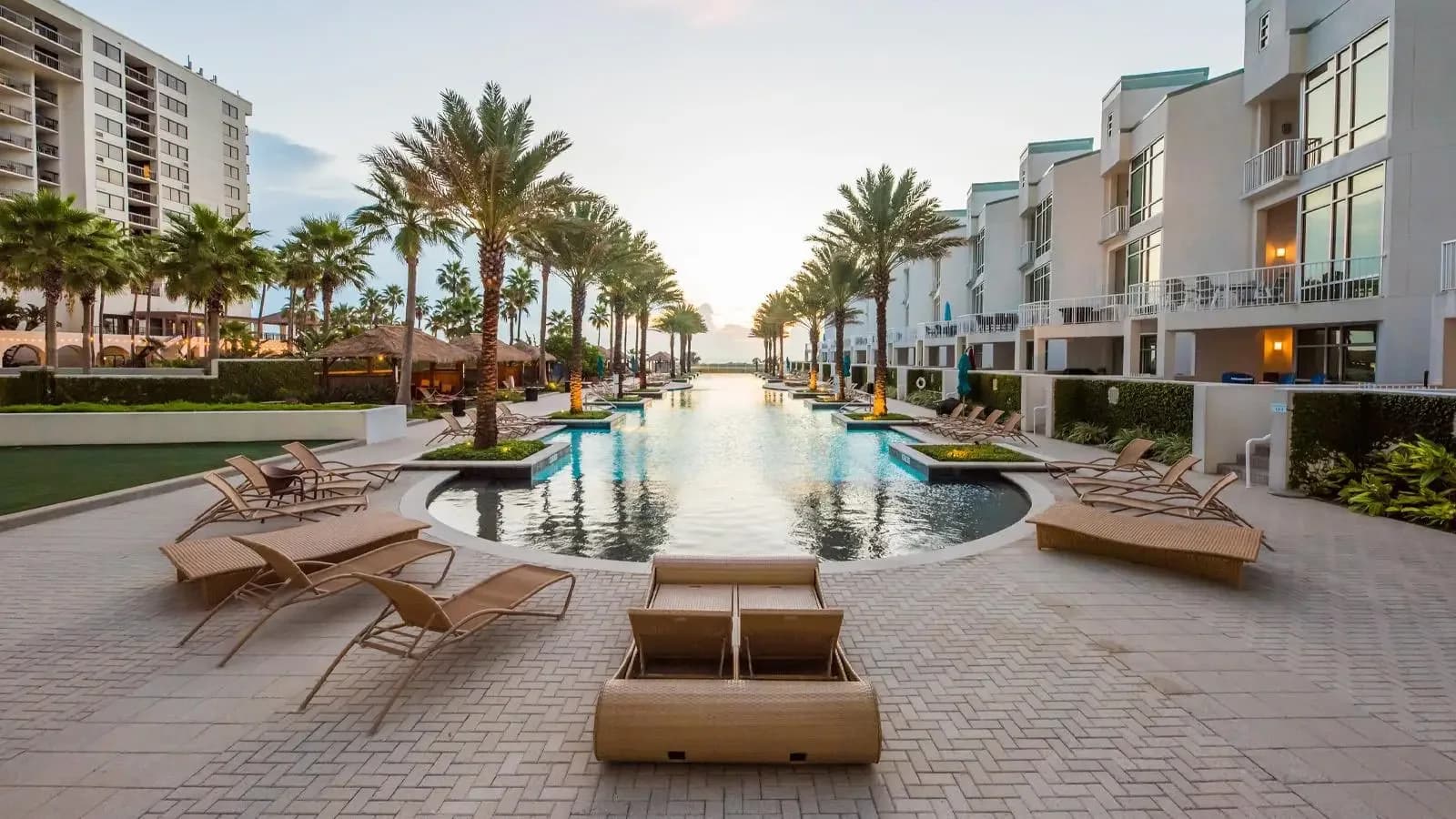 Palm-lined pool with lounge chairs between condo buildings on South Padre Island